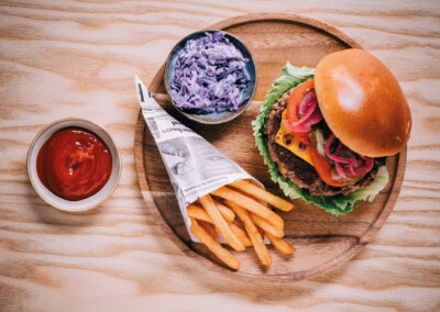 Holzteller mit Burger, Pommes und Krautsalat